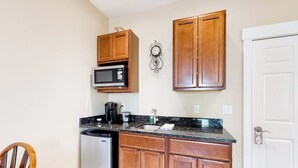 A compact kitchen with wooden cabinets, a microwave, a coffee maker, and a dishwasher. - Lovely downtown Northeast Harbor suite near the water and near Acadia (Northeast Harbor)