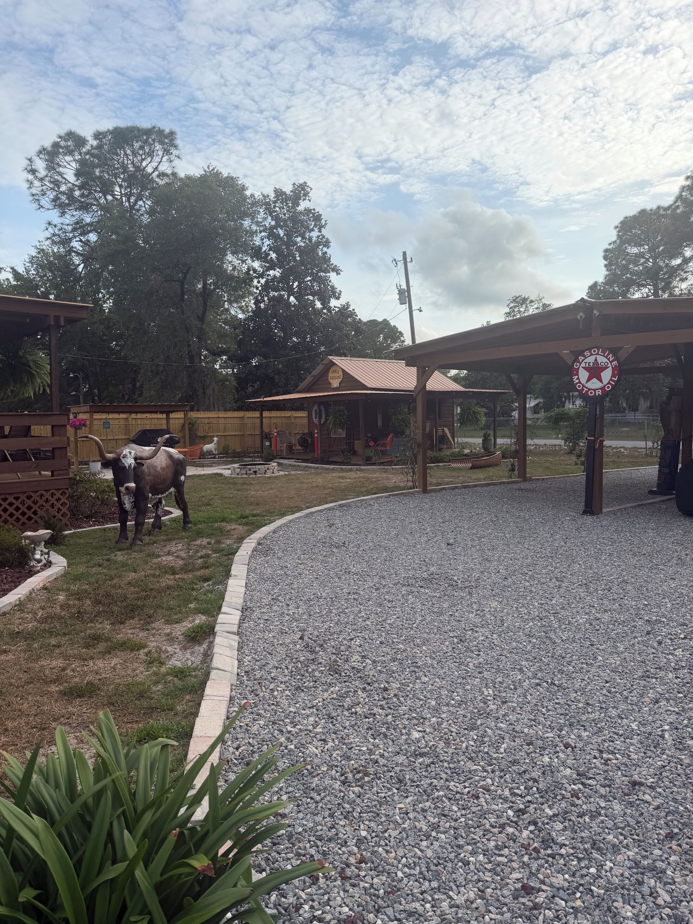 A rustic outdoor area with a gravel path, wooden structures, and a Texaco gas station sign.