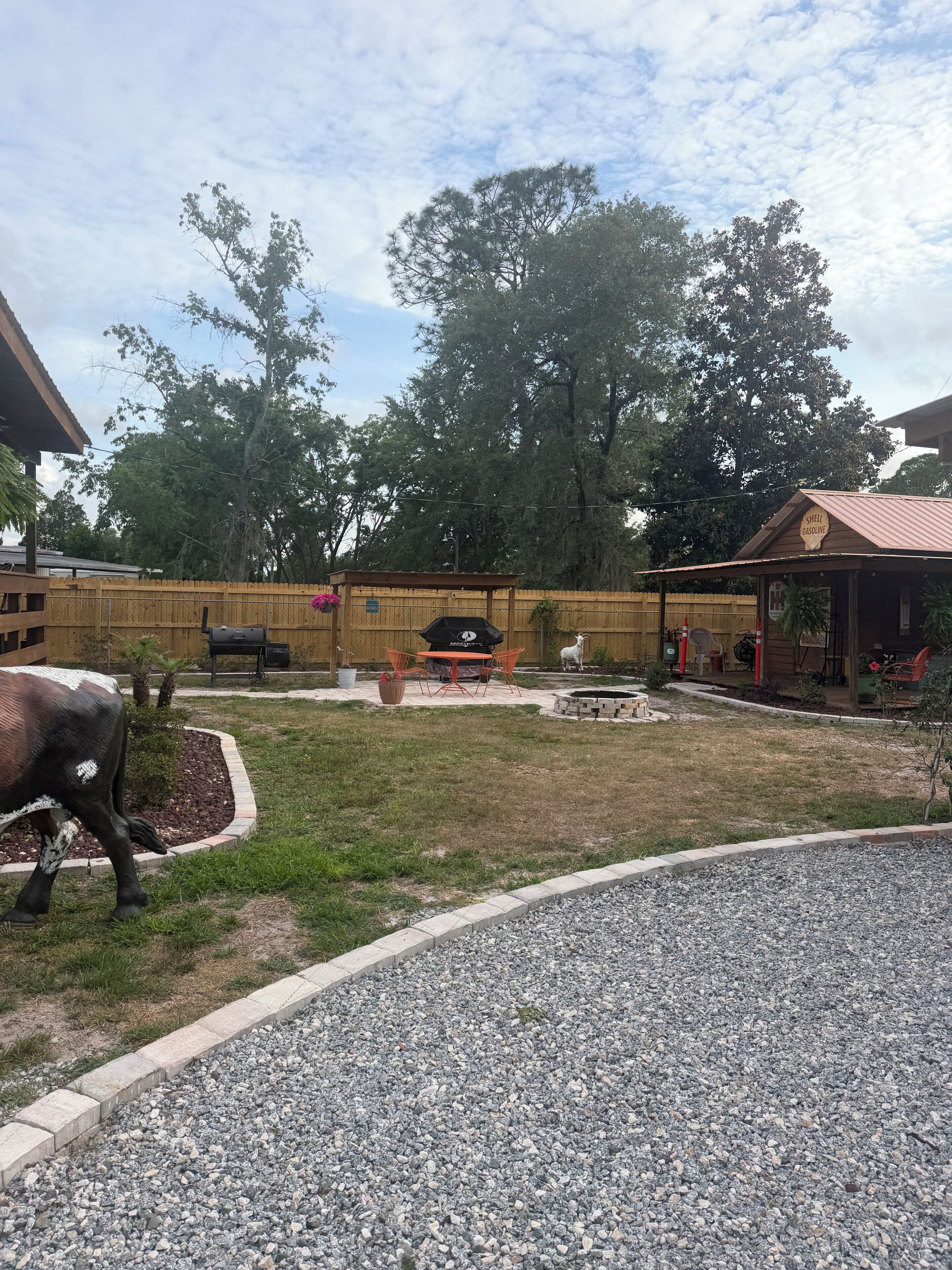 Ein Garten mit Grillplatz, Holzzaun und einem Kiesweg.
