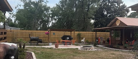 A backyard with a barbecue area, a wooden fence, and a gravel path.