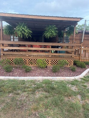 A wooden deck with a covered area, outdoor seating, and potted plants. - Blue Sky Bungalow - 1-bedroom bungalow in Homosassa located just off 19! (Homosassa)