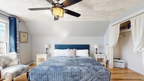 A bedroom with a bed, bedside tables, a chair, a ceiling fan, and a window. - Dog-friendly home with deck, pool table, & firepit - walk to downtown Boothbay (Boothbay Harbor)