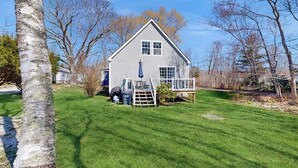 A single-story house with a front porch, a small deck, and a well-maintained lawn. - Dog-friendly home with deck, pool table, & firepit - walk to downtown Boothbay (Boothbay Harbor)