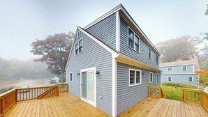 A two-story house with a deck, a garage, and a visible driveway. - Boothbay Harbor Home with Water Views | Near Dining & Whale Watching (Boothbay Harbor)