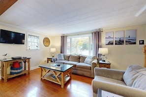Ein Wohnzimmer mit Sofa, Couchtisch, Fernseher und Kunstwerk an der Wand.