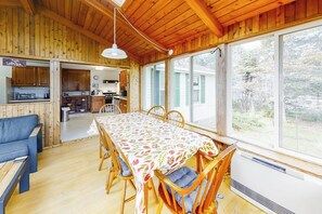 Un interior de madera con una mesa de comedor, sillas, un sofá y una zona de cocina.