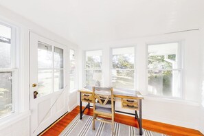 Ein Zimmer mit Schreibtisch, Stuhl und großen Fenstern.