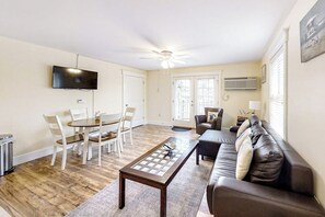 A living room with a dining table, chairs, a sofa, a TV, and a ceiling fan. - Water-view condo at Sheepscot Harbour Resort with deck, full kitchen, and WiFi (Edgecomb)