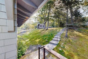 A house with a covered porch, a grassy yard, and a stone staircase leading to a door. - Ocean Point Colony I- Charming Cottage: Deepwater Dock, Panoramic Linekin Bay Views, Near Village (East Boothbay)