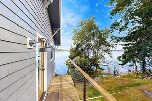 A wooden deck leading to a house with a view of a lake and dock. - Ocean Point Colony I- Charming Cottage: Deepwater Dock, Panoramic Linekin Bay Views, Near Village (East Boothbay)