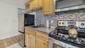 Una cocina moderna con electrodomésticos de acero inoxidable, armarios de madera y salpicadero de azulejos.