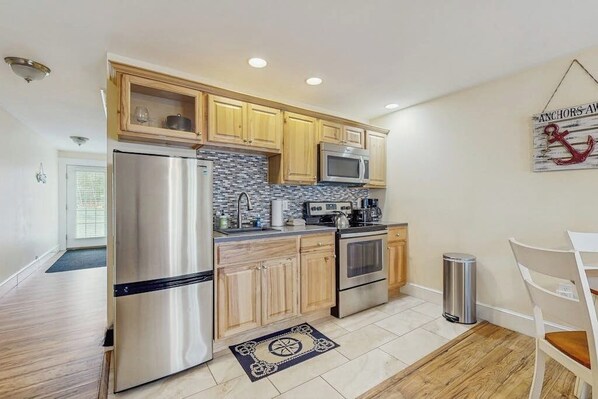 A modern kitchen with wooden cabinets, stainless steel appliances, and a tiled backsplash.