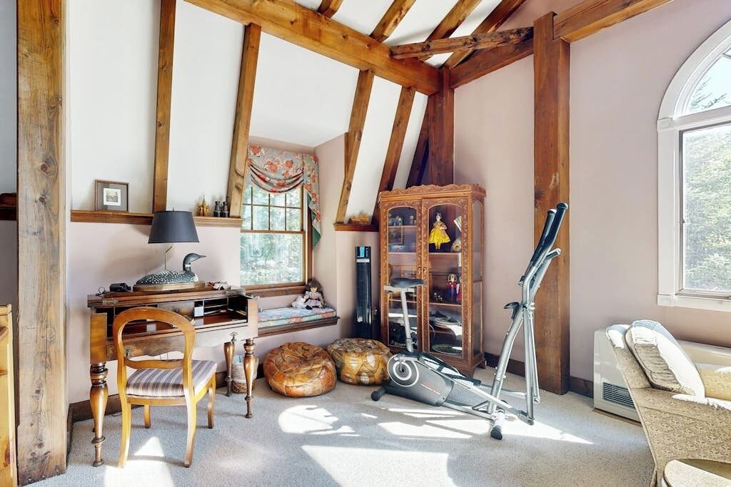 Une pièce comprenant un bureau en bois, une chaise, un placard et une fenêtre.