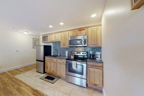 A modern kitchen with wooden cabinets, stainless steel appliances, and a tiled backsplash.