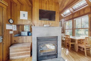A wooden interior with a fireplace, wooden furniture, and a clock on the wall. - Ocean Point Colony II- Waterfront Paradise with Dock, Sundeck & Epic Bay Views | Dog-Friendly (East Boothbay)