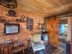 A wooden cabin interior with a vintage radio, a chair, a wooden cabinet, and a door.