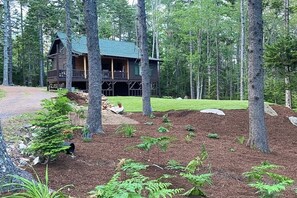 A cabin with a porch, surrounded by a forest.