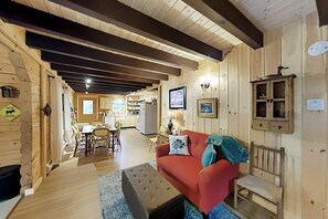 A wooden interior with a red sofa, dining area, kitchen, and a wooden bench.