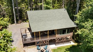A cabin with a covered porch, outdoor seating, and a stone fire pit.