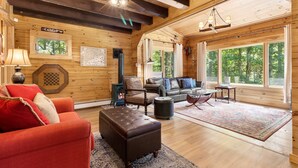 A cozy cabin interior with a fireplace, a sofa, a coffee table, and a dining area.
