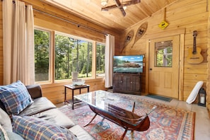 A wooden interior with a sofa, television, and a guitar. - Sprucewold Cabin-  w/ Private Beach Club Access Dog-friendly (Boothbay Harbor)