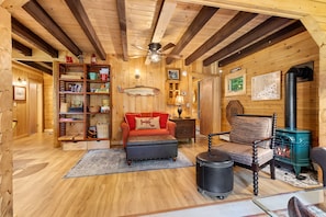 A cozy log cabin interior with a fireplace, a sofa, a reading nook, and a wooden bookshelf. - Sprucewold Cabin-  w/ Private Beach Club Access Dog-friendly (Boothbay Harbor)