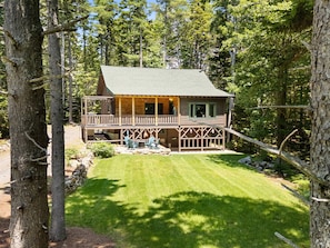 A cabin with a porch, a fire pit, and a well-maintained lawn. - Sprucewold Cabin-  w/ Private Beach Club Access Dog-friendly (Boothbay Harbor)