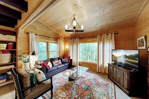 A cozy cabin interior with a sofa, television, and a patterned rug.