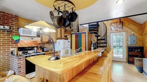 A kitchen with a wooden island, hanging pots, a microwave, and a brick wall. - Dog-Friendly Lakefront Home w/ Deck, Firepit, Water Views & Games (Rockwood)