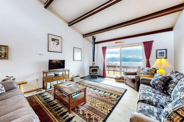 A living room with a fireplace, sofa, television, and a view of the outdoors.
