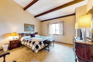 A bedroom with a bed, nightstand, dresser, lamp, and a window with curtains.