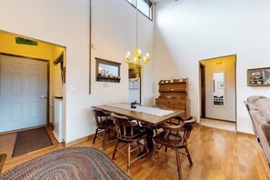 Un coin repas avec une table et des chaises en bois, un lustre et un miroir au-dessus de la table.