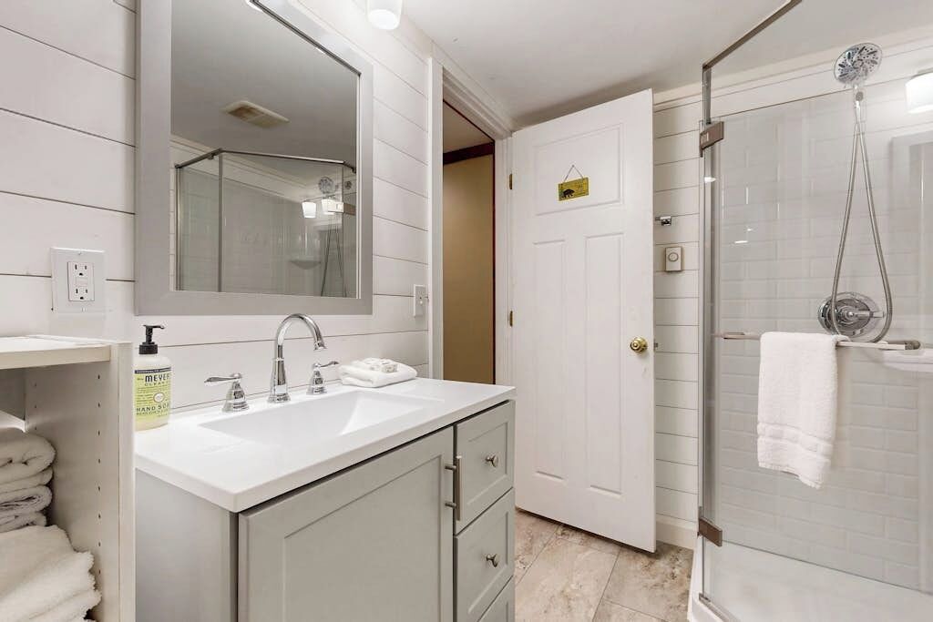A bathroom with a white sink, mirror, and shower.