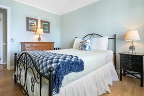 A bedroom with a bed, dresser, nightstand, and wall art. - Waterfront Oasis - Charming home with stunning bay views, sunroom, gazebo, deck (Trenton)