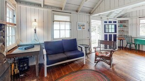 A cozy room with a blue sofa, a wicker chair, a small table, and a lamp. - Dog-friendly oceanfront cottage with views (St. George)