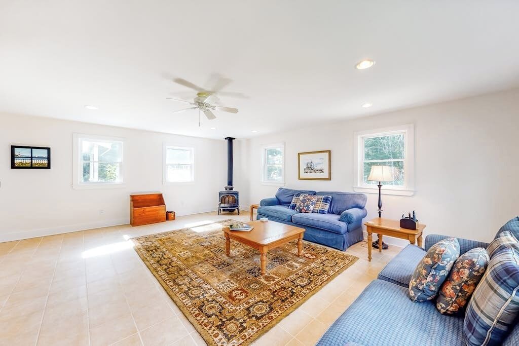 A spacious living room with a large window, a blue sofa, a wooden coffee table, and a fireplace.