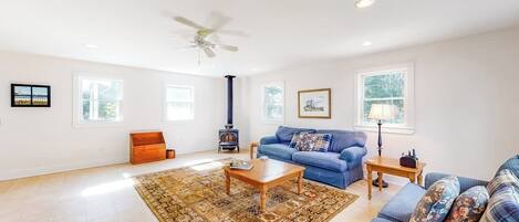 A spacious living room with a large window, a blue sofa, a wooden coffee table, and a fireplace.