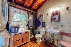 Een praktische badkamer met een wasmachine, wastafel, toilet en spiegel.
