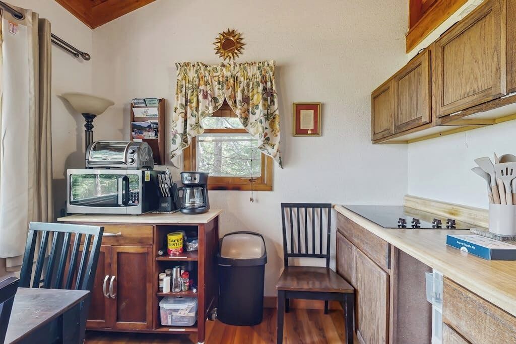 A compact kitchen with a microwave, toaster, coffee maker, and wooden cabinets.