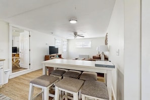 A spacious living area with a central island, seating, a ceiling fan, and a television.
