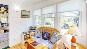 A cozy room with a wicker sofa, a wooden coffee table, and a window with blinds. - Sea View- Dog-friendly bay view home - water views (Boothbay Harbor)