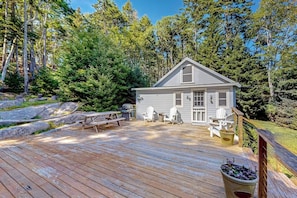A cabin with a deck, surrounded by trees.