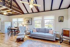 A spacious living room with a sofa, chairs, a dining table, and a ceiling fan.