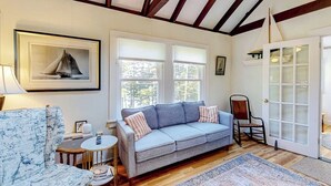 A room with a sofa, a chair, a small table, a framed picture, and a door with frosted glass panels. - Sea View- Dog-friendly bay view home - water views (Boothbay Harbor)