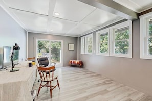 A spacious room with a large window, a desk with a chair, and a small table with a chair. - Charming Lakefront Apartment with Deck, Patio and BBQ Grill (Orland)