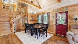 L’intérieur d’un chalet en bois comprend un coin repas, un escalier et une porte rouge portant l’inscription « SUNRISE ».