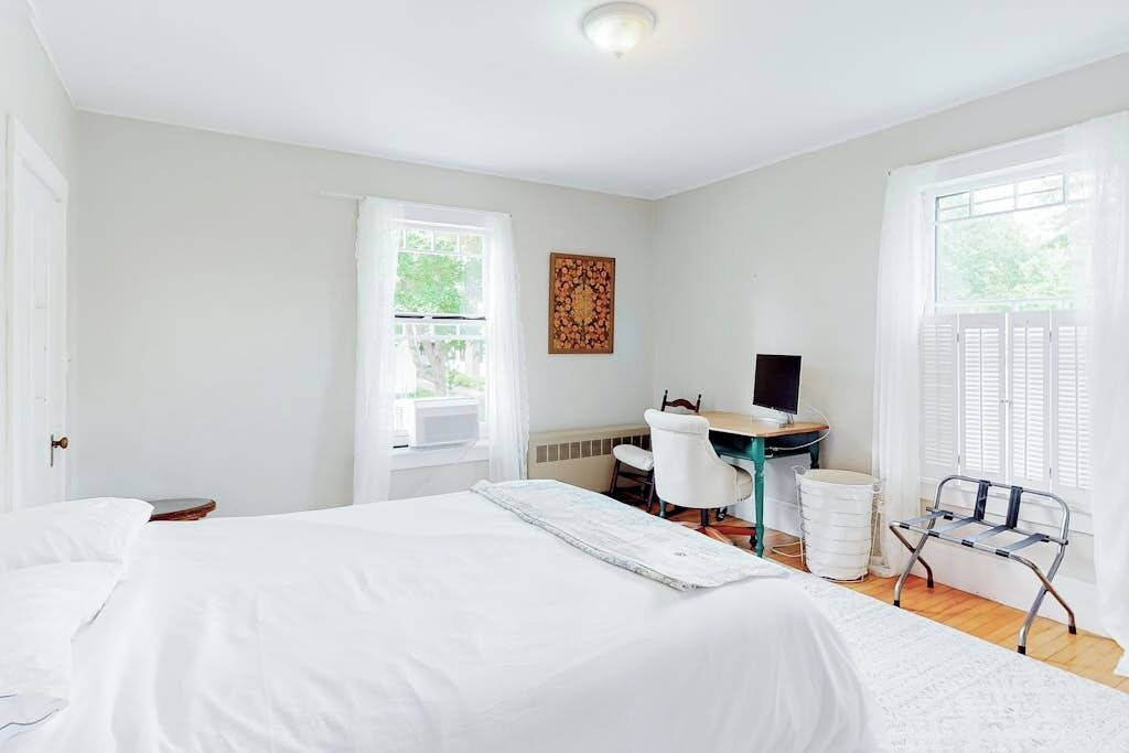 A bedroom with a bed, a desk, a chair, and a window.