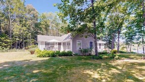 A single-story house with a covered porch, surrounded by a well-maintained lawn and trees.