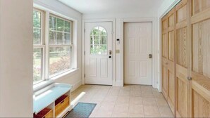A hallway with a bench, a door, and a window.