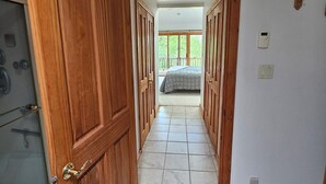 Een gang met houten deuren die leiden naar een slaapkamer met een bed en een balkon.